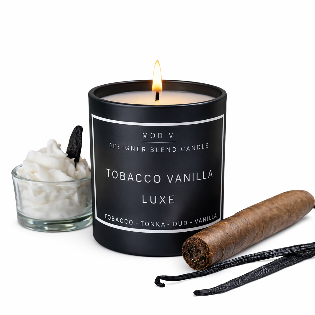 Candle labeled 'Tobacco Vanilla Luxe' with a glass of white flowers and a vanilla bean on a white background