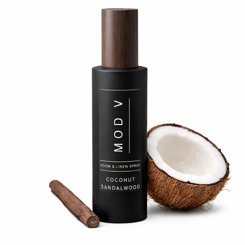 Black room & linen spray bottle with wooden cap, coconut, and cinnamon stick on a white background