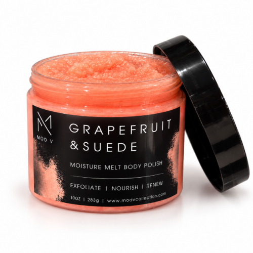 A jar of grapefruit and suede body polish by MOD V, showing the textured orange-pink polish inside, with its black lid leaning against the jar on a white background.