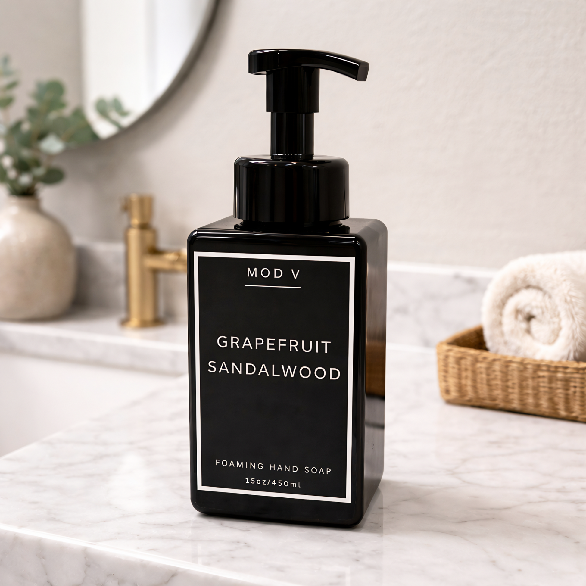 Black foaming hand soap bottle labeled 'Grapefruit Sandalwood' on a bathroom counter.