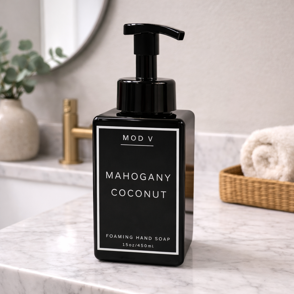 Black foaming hand soap bottle labeled 'Mahogany Coconut' on a marble countertop.