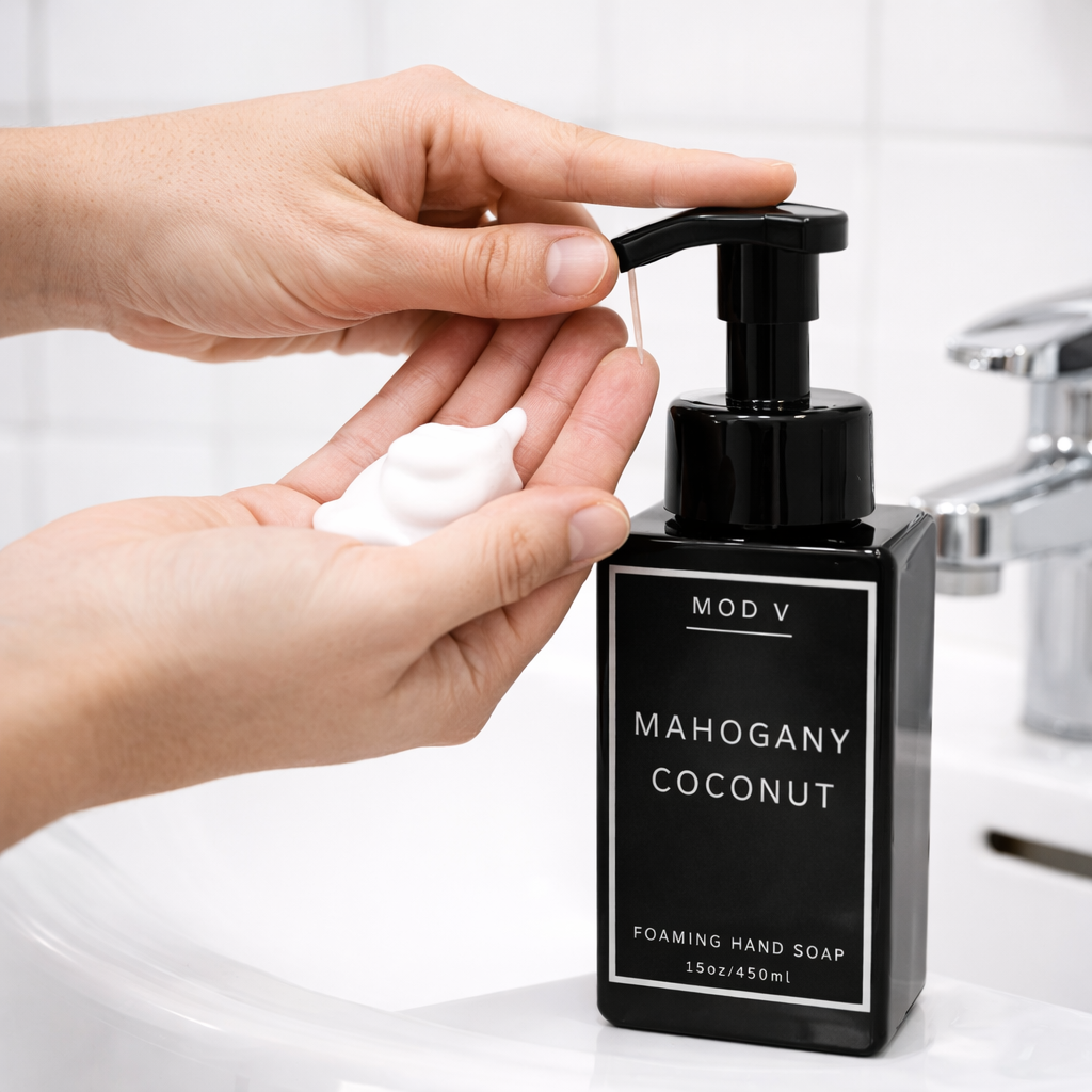 Hand holding a pump of MOD V Mahogany Coconut foaming hand soap.