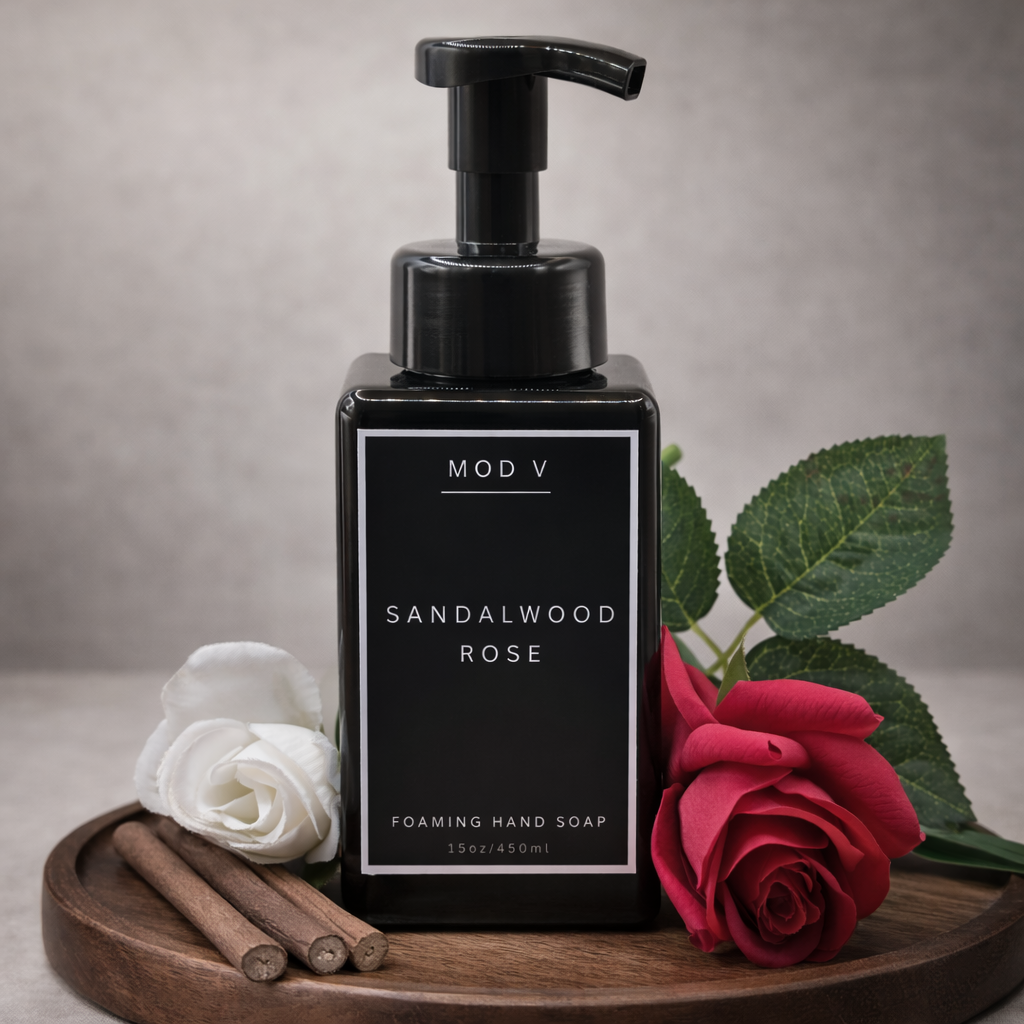 Black pump bottle of Sandalwood Rose foaming hand soap on a wooden tray with roses and cinnamon sticks.