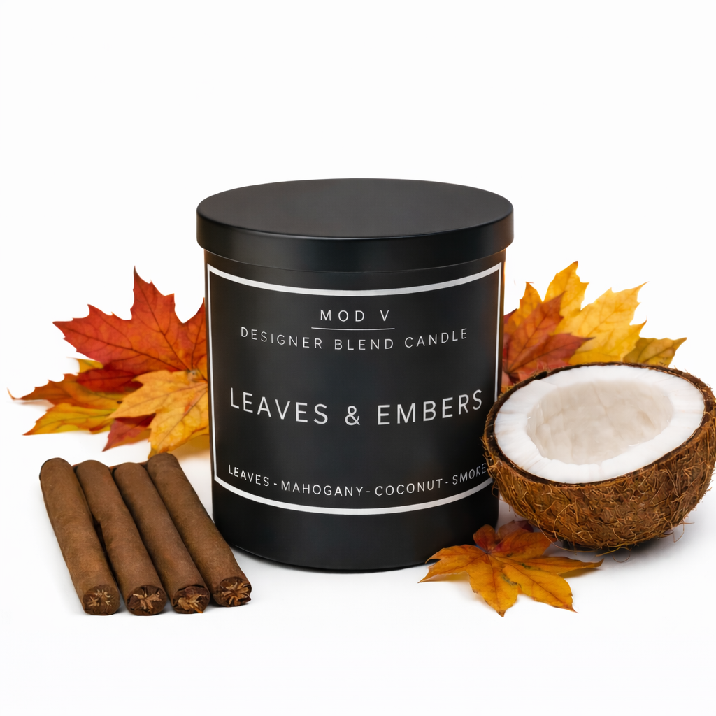 Candle labeled 'Leaves & Embers' with cinnamon sticks and a coconut on a white background