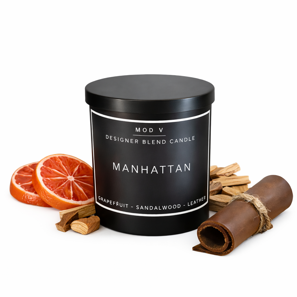 Designer blend candle labeled 'Manhattan' with grapefruit, sandalwood, and leather elements on a white background.
