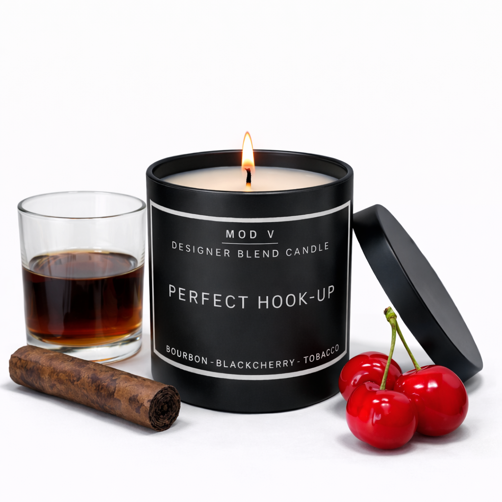 Candle labeled 'Perfect Hook-Up' with a glass of dark liquid, cinnamon stick, and cherries on a white background