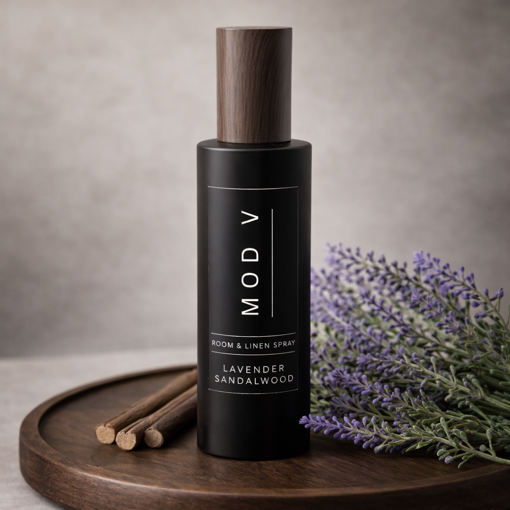 Black bottle of MOD V lavender sandalwood room spray on a wooden tray with lavender and cinnamon sticks.