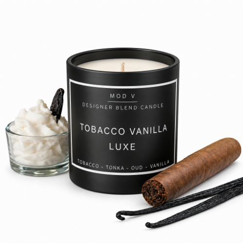A black candle jar labeled 'MOD V DESIGNER BLEND CANDLE TOBACCO VANILLA LUXE' on a white background, styled with a small glass bowl of whipped cream and vanilla bean pieces, plus a cigar and vanilla pods.
