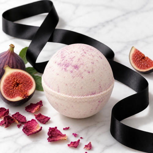 A round bath bomb with a light pink and purple marbled pattern sits on a white marble surface, styled with fresh figs, dried rose petals, and a flowing black ribbon.